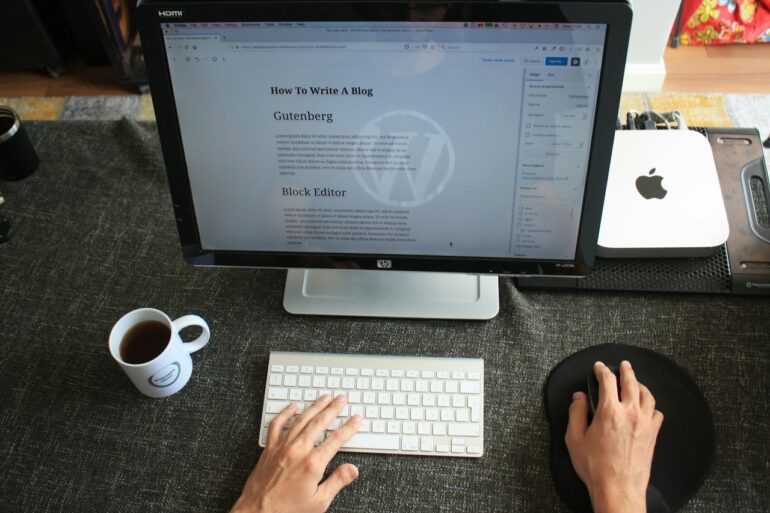 a PC on top of a desk and a person writing a blog post